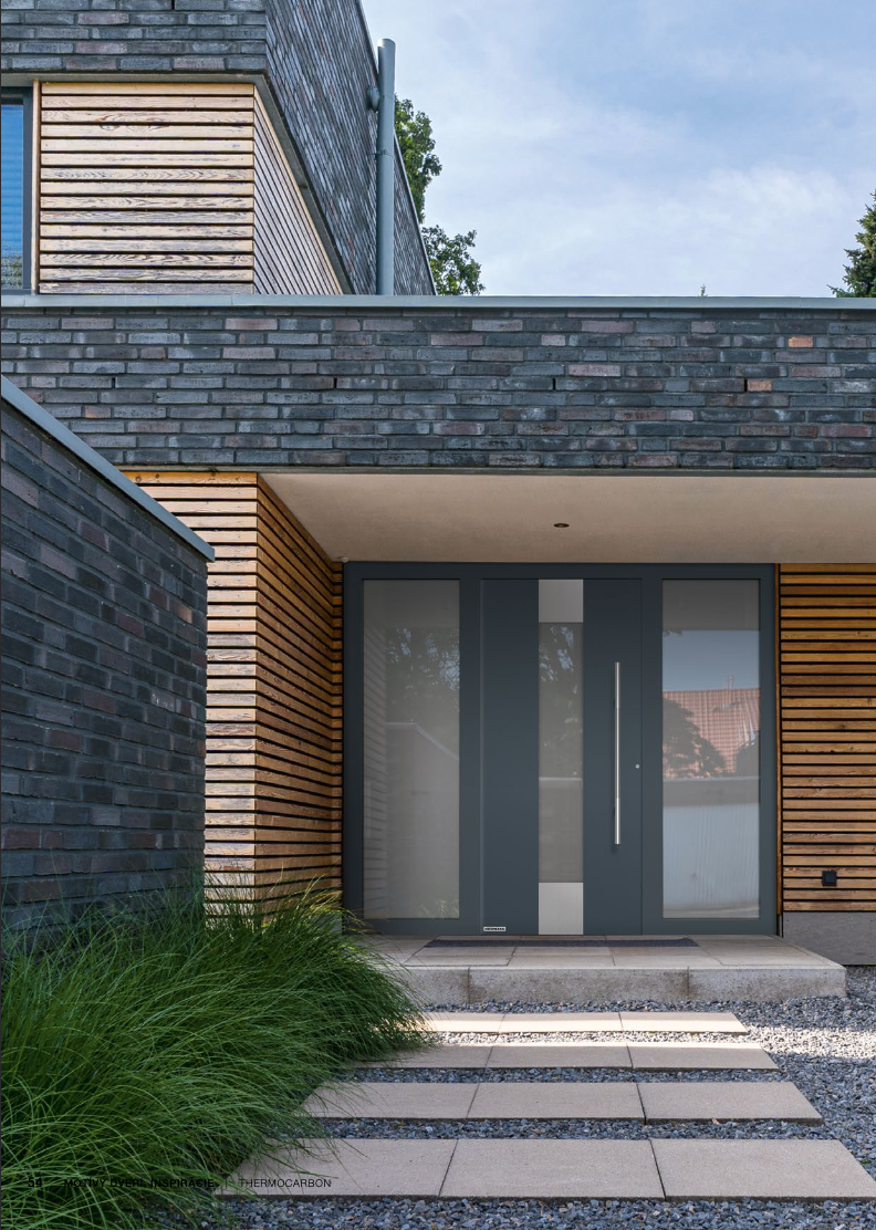 Dvere Hormann - Antracitové presklené vchodové dvere so sklom Satinato, moderná fasáda s antracitovou tehlou a dreveným obkladom na rodinnom dome.